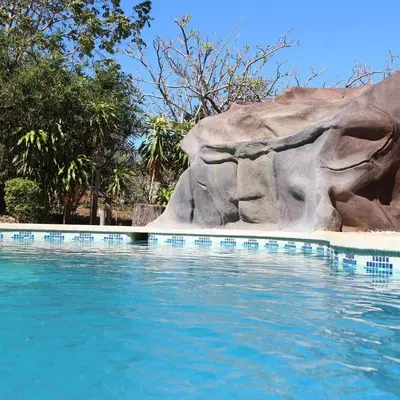 a swimming pool next to a large rock at Cabinas Liz in Veintisiete de Abril