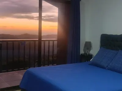 a bedroom with a bed and a balcony with a sunset at Finca Alta Vista Monteverde in Monteverde Costa Rica