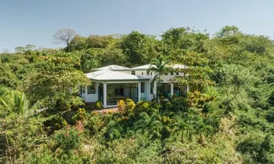a house in the middle of a hill with trees at Driftwood ocean view in Playa Ostional