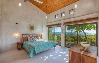 a bedroom with a bed and a large window at Driftwood ocean view in Playa Ostional