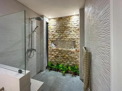 a bathroom with a shower and a stone wall at Eben-ezer #1 in Uvita