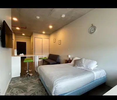 a bedroom with a bed and a chair and a clock at Studio Apartment URBN Escalante in San José