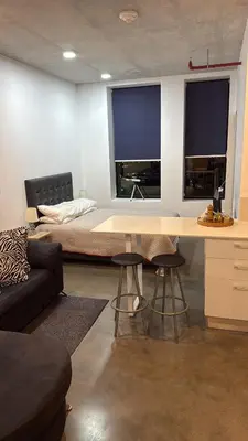 a bedroom with a bed and a desk with two windows at Studio Apartment URBN Escalante in San José