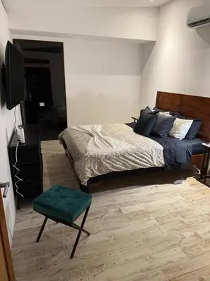 a bedroom with a bed and a television and a green stool at Casa Grande Pura Vida in Fortuna