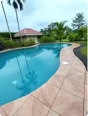 a swimming pool with a concrete walkway around a swimming pool at Casa Grande Pura Vida in Fortuna