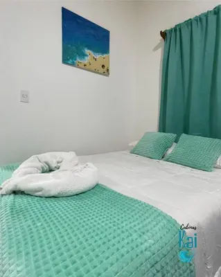 a bedroom with two beds with green and white sheets at Cabinas Kai in Quepos