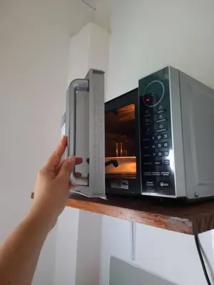 a person holding a cell phone in front of a microwave at Cabinas Kai in Quepos