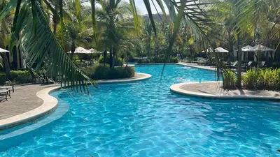 a swimming pool with blue water and palm trees at Luxury Pacifico 3 Bedroom 2 Bath with 300 Mbps WI-FI in Coco