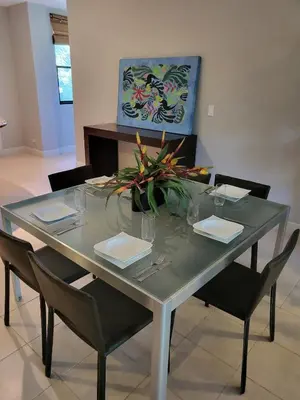 a glass table with chairs and a vase of flowers on it at Luxury Pacifico 3 Bedroom 2 Bath with 300 Mbps WI-FI in Coco