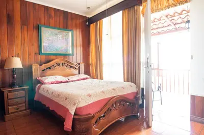 a bedroom with a bed with a wooden wall at Casa Hotel Sura in San José