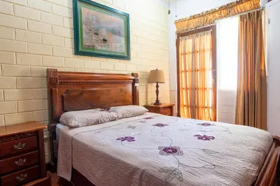 a bedroom with a bed with a floral bedspread at Casa Hotel Sura in San José