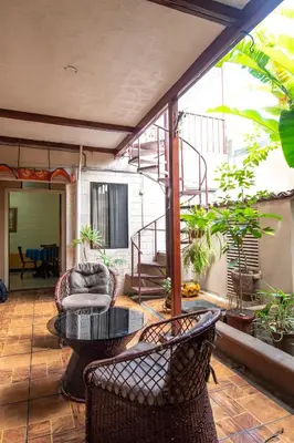 a patio with a table and chairs and a staircase at Casa Hotel Sura in San José