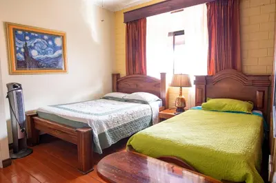 a bedroom with two beds and a window at Casa Hotel Sura in San José