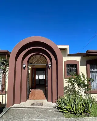 a building with an archway in front of it at La Dehesa B&B en San Joaquín de Flores in Heredia