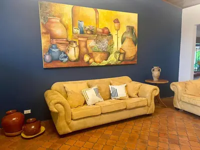 a couch in a living room with a painting on the wall at La Dehesa B&B en San Joaquín de Flores in Heredia
