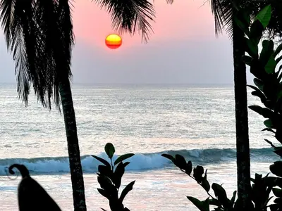 a sunset over the ocean from a beach with palm trees at Santa Teresa Manzanillo Walk to Beach, New Home, Center of Tranquil Town in Boca de Ario