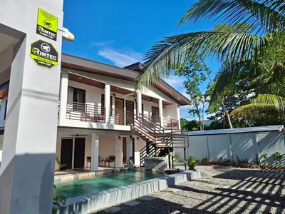 a house with a swimming pool in front of it at AJ Suites - Modern Beach Apartments with Pool and Full Kitchen in Uvita