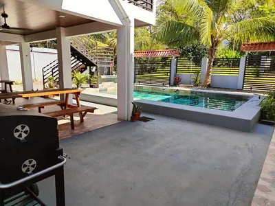 a patio with a pool and a table and a bench at AJ Suites - Modern Beach Apartments with Pool and Full Kitchen in Uvita
