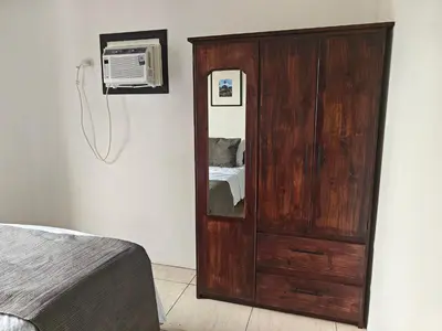 a bedroom with a wooden cabinet and a tv at AJ Suites - Modern Beach Apartments with Pool and Full Kitchen in Uvita