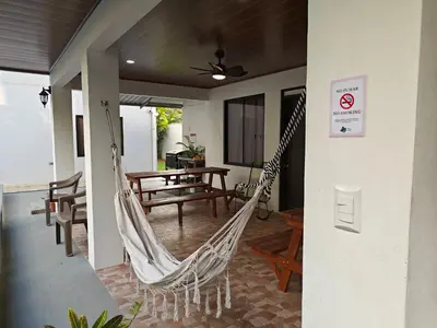 a porch with a hammock and a table and chairs at AJ Suites - Modern Beach Apartments with Pool and Full Kitchen in Uvita