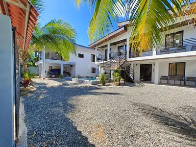 a house with palm trees and a gravel driveway at AJ Suites - Modern Beach Apartments with Pool and Full Kitchen in Uvita