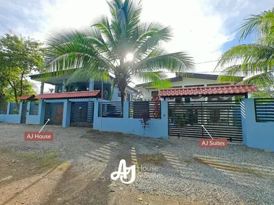a house with a palm tree in front of it at AJ Suites - Modern Beach Apartments with Pool and Full Kitchen in Uvita