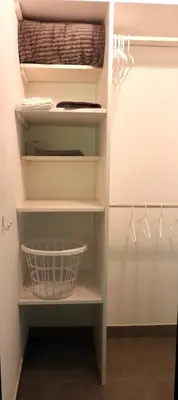 a walk in closet with white shelves and a basket at Colibri Jungle Casita in Dominical
