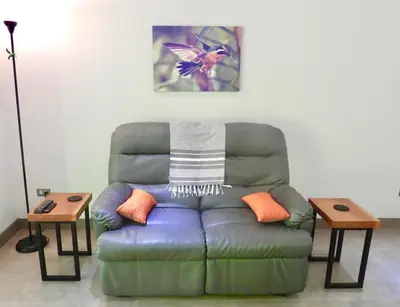 a living room with a couch and two tables at Colibri Jungle Casita in Dominical