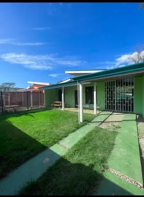 a green house with a lawn in front of it at Casa Jicaro in Nosara