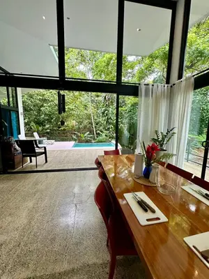 a dining room with a table and a large window at Casa de Bosque con Piscina in Naranjito