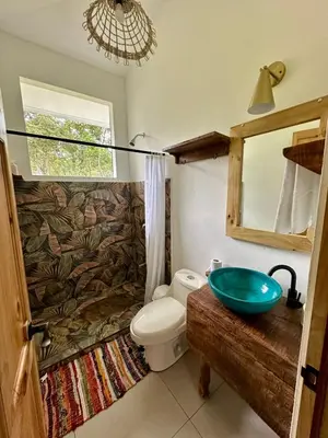 a bathroom with a toilet and a glass sink at Casa de Bosque con Piscina in Naranjito