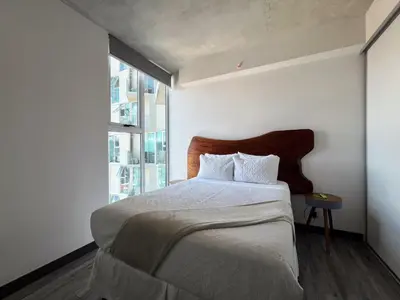 a bedroom with a bed with a wooden headboard and a window at Lux at 15, Pool, Gym and Stylish City Stay in Hatillo