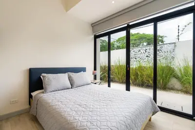 a bedroom with a bed and a large window at Sprawling Modern Property with a Tranquil Outdoor Living Space swimming pool and a private Casita in Playa Flamingo