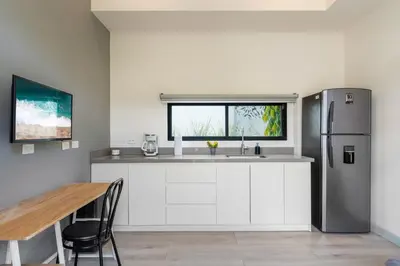 a kitchen with a stainless steel refrigerator and a table at Sprawling Modern Property with a Tranquil Outdoor Living Space swimming pool and a private Casita in Playa Flamingo