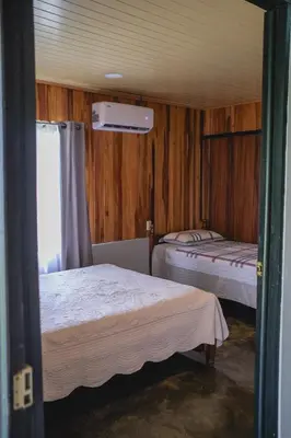two beds in a room with wooden walls and a window at Blanca's House in Fortuna