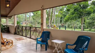 two blue chairs and a table on a porch at House in the Woods in Guápiles