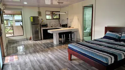 a bedroom with a bed and a kitchen with a desk at House in the Woods in Guápiles