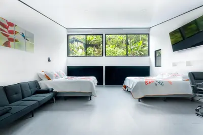 a bedroom with two beds and a couch and windows at Route to Cerro Urán - Chirripó in Rivas
