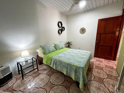 a bedroom with a bed with a green comforter at Apartment 5 -10 minutes away BY CAR from Manuel Antonio beach! in Quepos