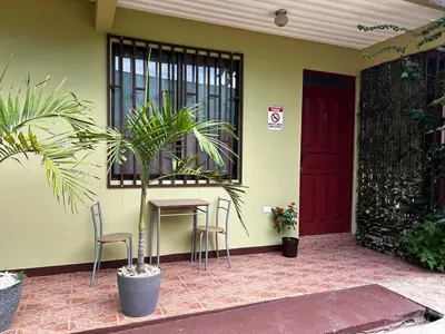 a house with a table and chairs and a red door at Apartment 5 -10 minutes away BY CAR from Manuel Antonio beach! in Quepos