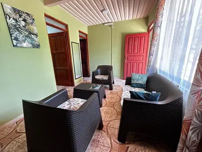 a living room with two chairs and a red door at Apartment 5 -10 minutes away BY CAR from Manuel Antonio beach! in Quepos