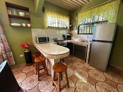 a kitchen with a refrigerator and a table and stools at Apartment 5 -10 minutes away BY CAR from Manuel Antonio beach! in Quepos