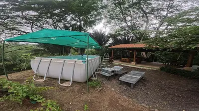 a pool with a green umbrella and a table and bench at Lapas House in Esperanza