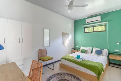a bedroom with a bed with a green wall at Colores Beach Apartments Santa Teresa in Santa Teresa Beach