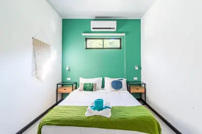a bedroom with a bed with a green wall at Colores Beach Apartments Santa Teresa in Santa Teresa Beach