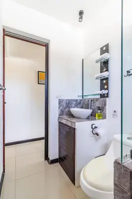 a bathroom with a sink and a toilet and a mirror at Colores Beach Apartments Santa Teresa in Santa Teresa Beach
