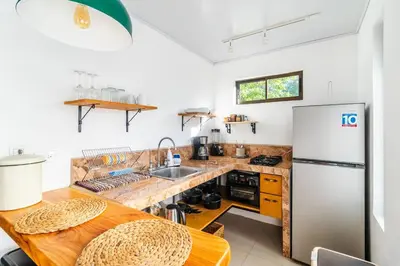 a kitchen with a wooden table and a refrigerator at Colores Beach Apartments Santa Teresa in Santa Teresa Beach