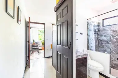 a bathroom with a toilet and a door and a sink at Colores Beach Apartments Santa Teresa in Santa Teresa Beach