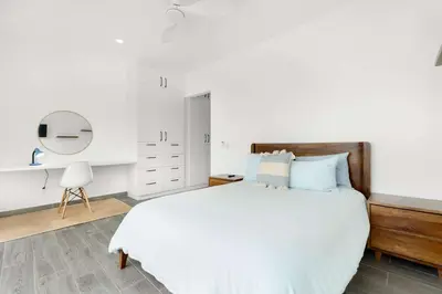 a white bedroom with a large bed and a mirror at 4BR Villa Oceanview and Infinity Pool in Brasilito