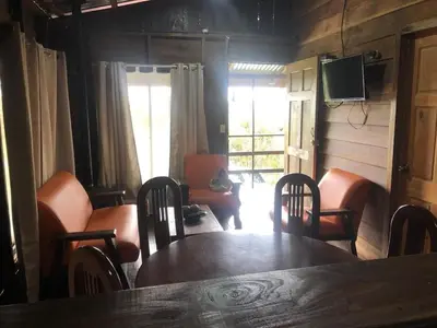 a dining room with a table and chairs and a television at Cabaña El Bosque in Turrialba